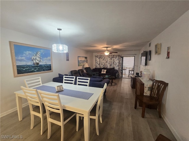 dining room with dark wood-type flooring and ceiling fan with notable chandelier