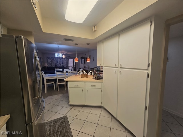 kitchen featuring stainless steel fridge, kitchen peninsula, hanging light fixtures, and white cabinetry