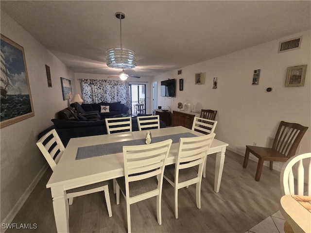 dining room featuring ceiling fan with notable chandelier and hardwood / wood-style floors