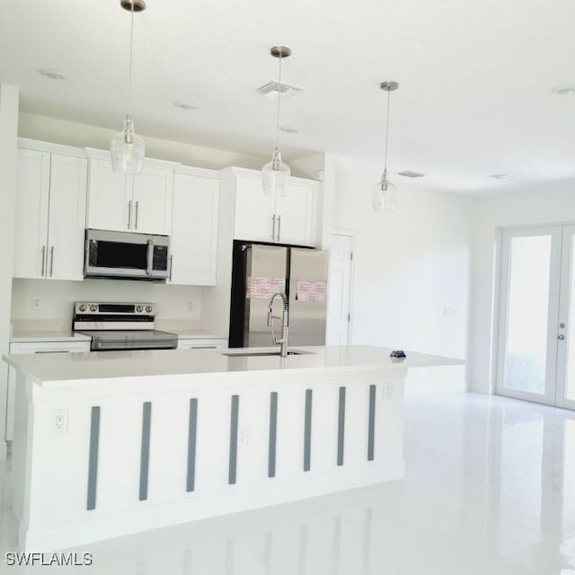 kitchen with white cabinetry, hanging light fixtures, stainless steel appliances, and a center island with sink