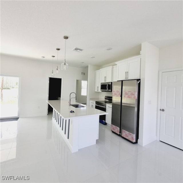 kitchen with appliances with stainless steel finishes, sink, an island with sink, pendant lighting, and white cabinets