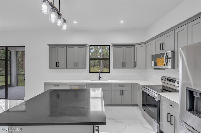 kitchen featuring decorative light fixtures, a center island, sink, and stainless steel appliances