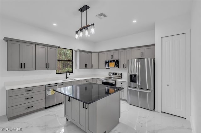 kitchen featuring stainless steel appliances, sink, a kitchen island, gray cabinets, and pendant lighting