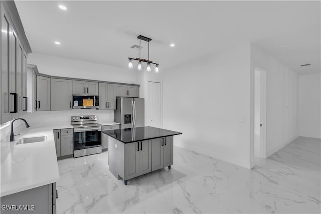 kitchen featuring stainless steel appliances, a kitchen island, decorative light fixtures, gray cabinets, and sink