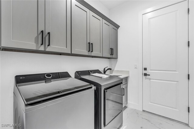 clothes washing area featuring cabinets, sink, and separate washer and dryer