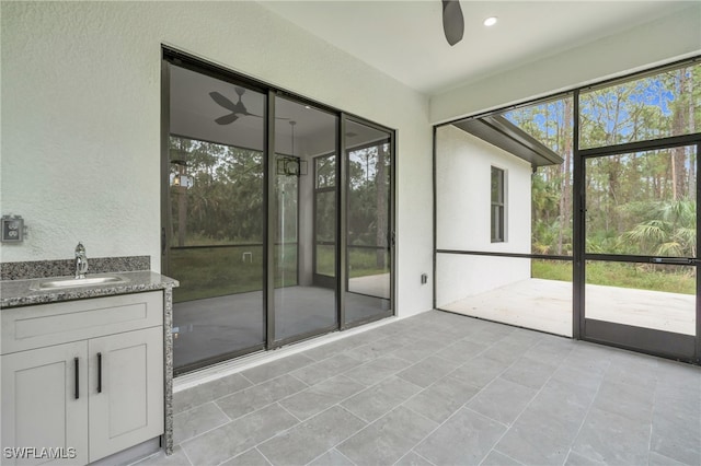 unfurnished sunroom with sink and ceiling fan