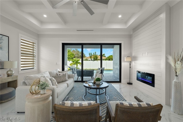 living room with beam ceiling, coffered ceiling, a large fireplace, and ceiling fan