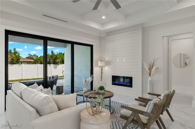 living room with a large fireplace, beam ceiling, and ceiling fan