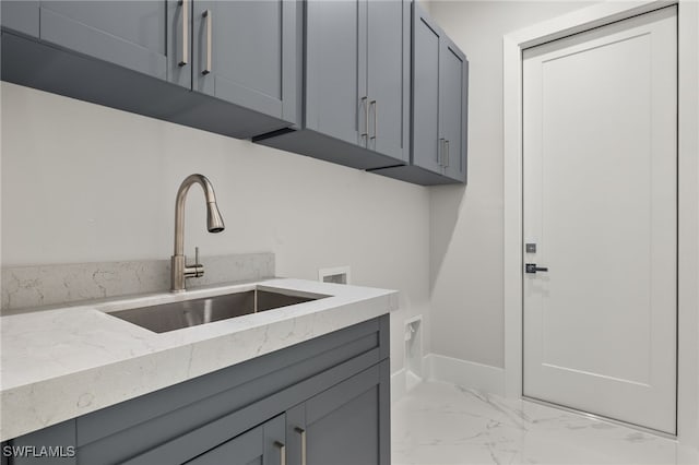 interior space with gray cabinets, sink, and light stone countertops