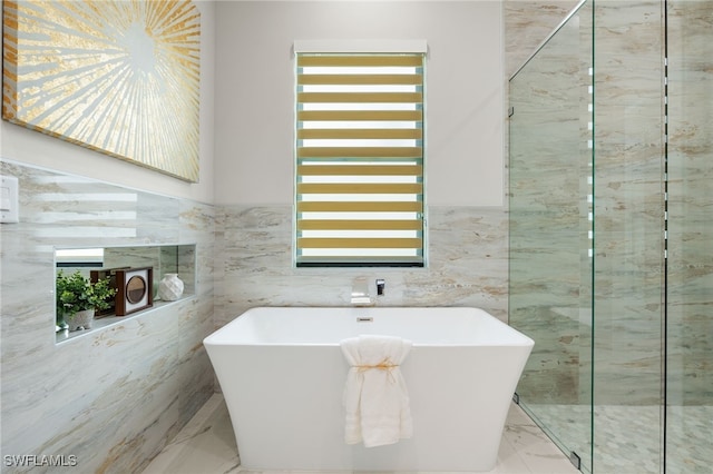 bathroom with tile walls, plenty of natural light, and a bathing tub