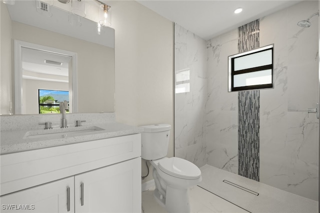 bathroom with vanity, a tile shower, and toilet