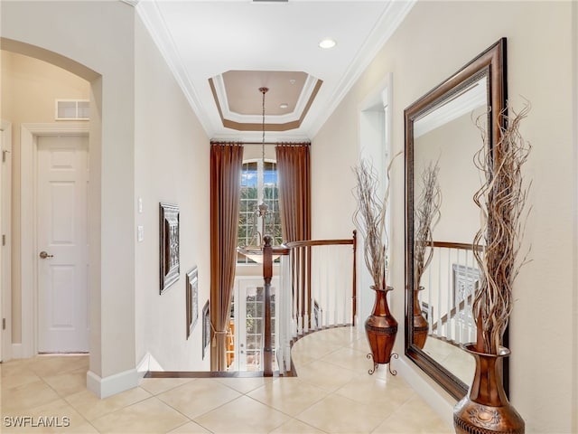 corridor featuring a raised ceiling, crown molding, and light tile patterned floors