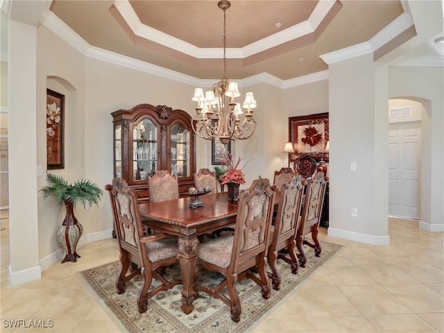 tiled dining area featuring ornamental molding, a tray ceiling, and a chandelier