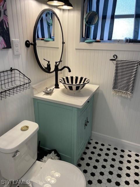 bathroom with vanity, toilet, and wooden walls