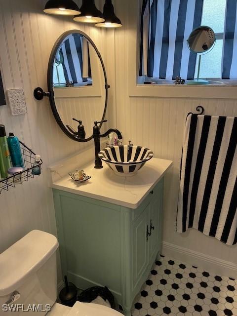 bathroom with wooden walls, vanity, and toilet