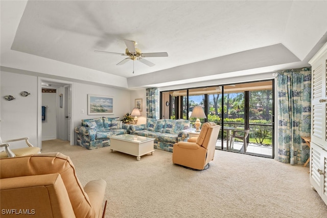 carpeted living room featuring ceiling fan and a tray ceiling