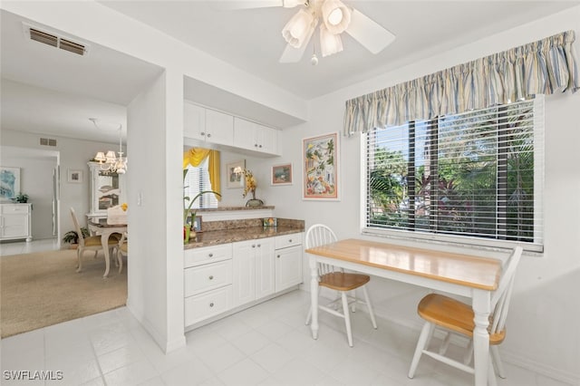 kitchen with light carpet, ceiling fan, dark stone countertops, decorative light fixtures, and white cabinetry