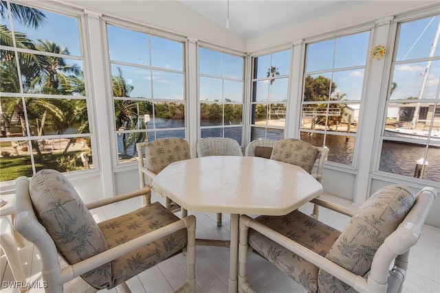 sunroom / solarium with a water view, lofted ceiling, and plenty of natural light