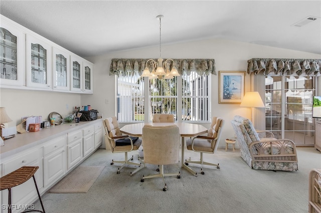 dining room featuring an inviting chandelier, light colored carpet, and vaulted ceiling