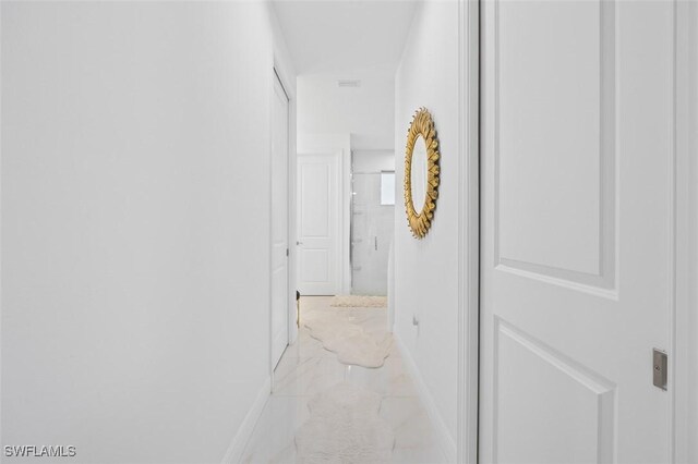 hallway with marble finish floor and baseboards