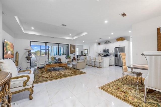 living area featuring recessed lighting, a raised ceiling, visible vents, and marble finish floor