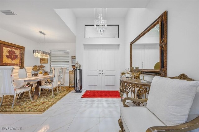 tiled entrance foyer featuring visible vents and an inviting chandelier