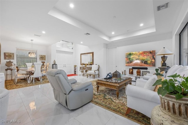 living room featuring a tray ceiling, visible vents, and recessed lighting