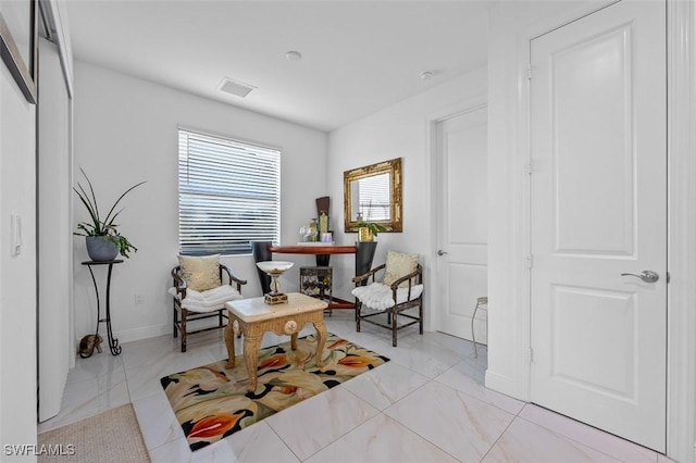 sitting room with marble finish floor, visible vents, and baseboards