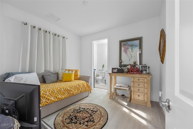 bedroom with ensuite bathroom and light hardwood / wood-style floors