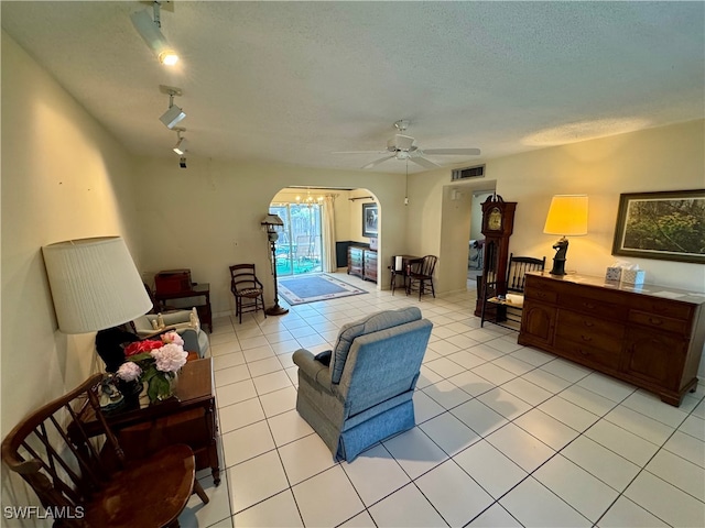 living room featuring ceiling fan, a textured ceiling, light tile patterned floors, and track lighting