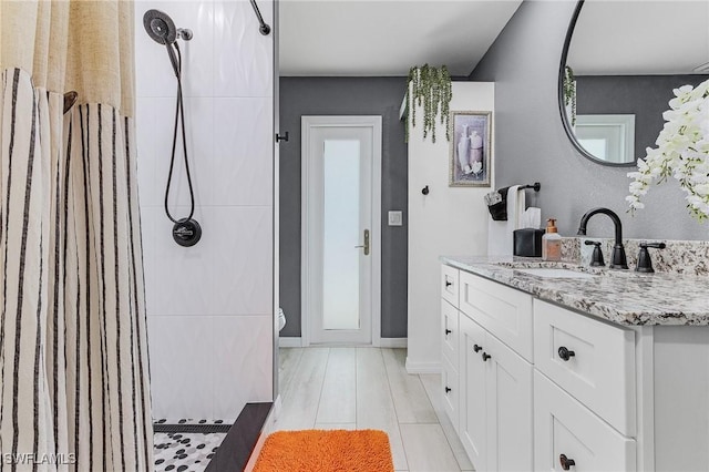 bathroom with vanity, toilet, a tile shower, and wood-type flooring