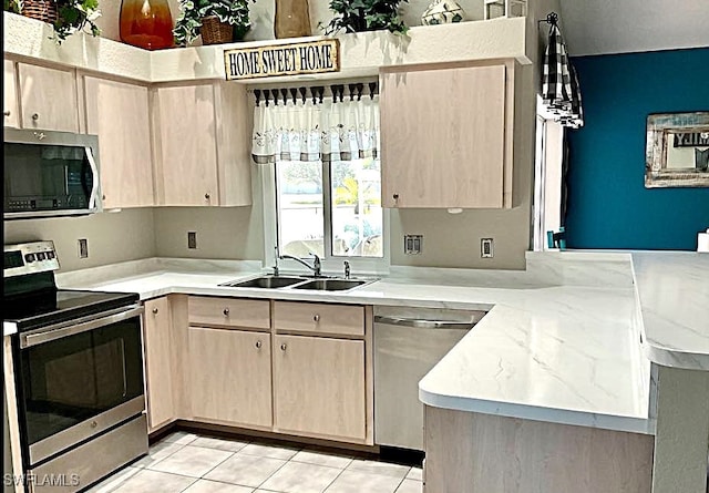 kitchen with light brown cabinets, sink, appliances with stainless steel finishes, light tile patterned flooring, and kitchen peninsula