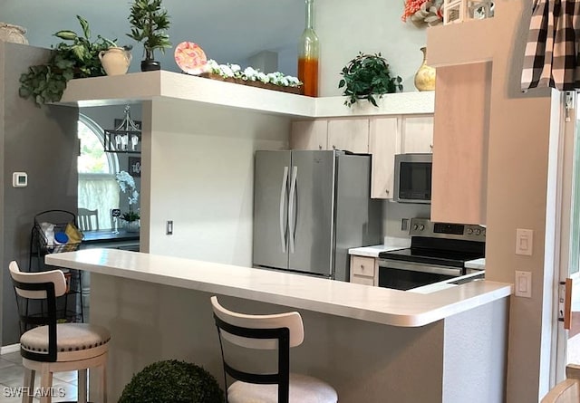 kitchen with a breakfast bar, appliances with stainless steel finishes, kitchen peninsula, and hanging light fixtures