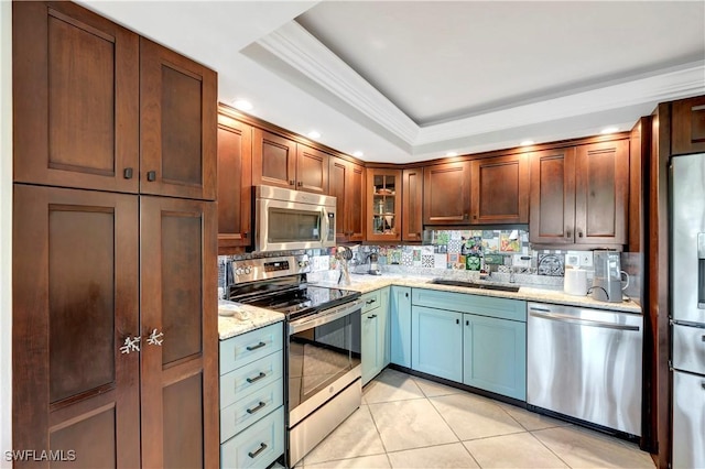 kitchen with a raised ceiling, sink, decorative backsplash, stainless steel appliances, and light stone countertops