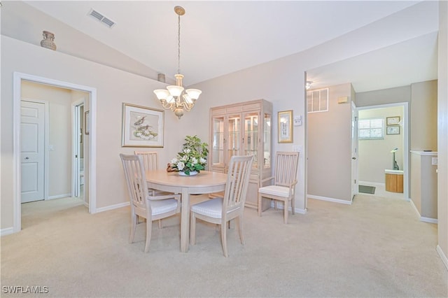 carpeted dining room featuring vaulted ceiling and an inviting chandelier