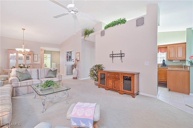 living room with ceiling fan with notable chandelier, light colored carpet, high vaulted ceiling, and sink