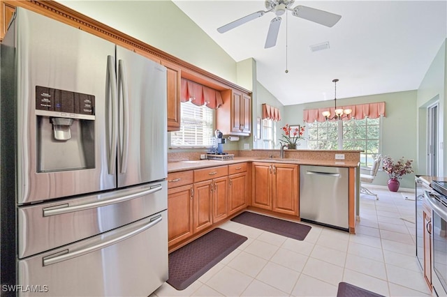 kitchen featuring sink, kitchen peninsula, pendant lighting, lofted ceiling, and appliances with stainless steel finishes