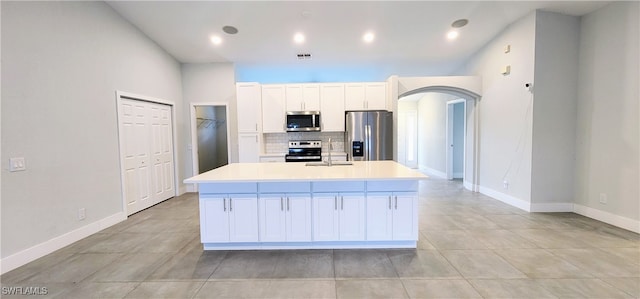 kitchen with white cabinetry, sink, stainless steel appliances, backsplash, and a kitchen island with sink