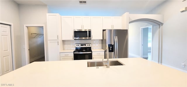 kitchen featuring white cabinets, sink, backsplash, and appliances with stainless steel finishes