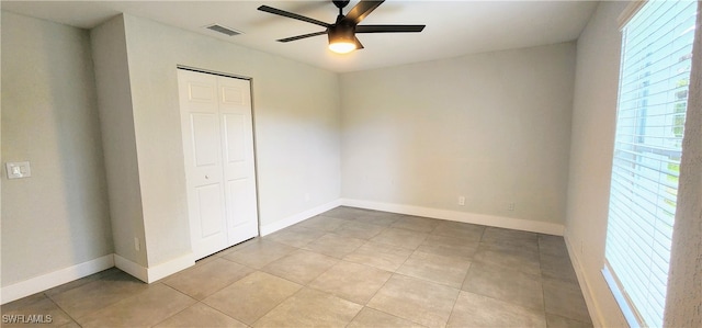 unfurnished bedroom with ceiling fan, light tile patterned flooring, and a closet