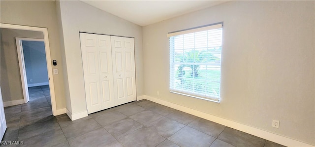 unfurnished bedroom featuring tile patterned floors, a closet, and lofted ceiling