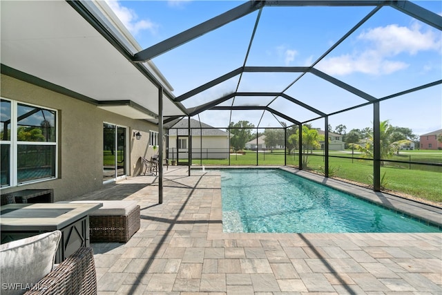 view of swimming pool with glass enclosure, a patio area, and a lawn