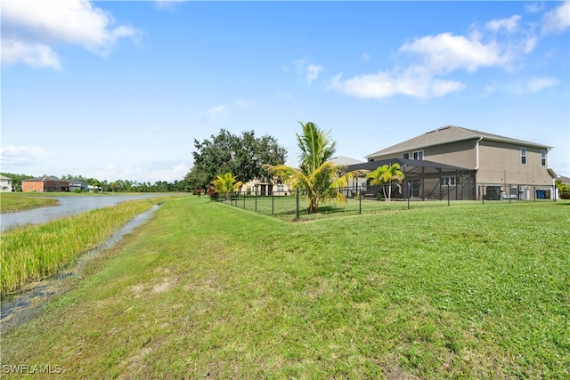 view of yard with a lanai and a water view