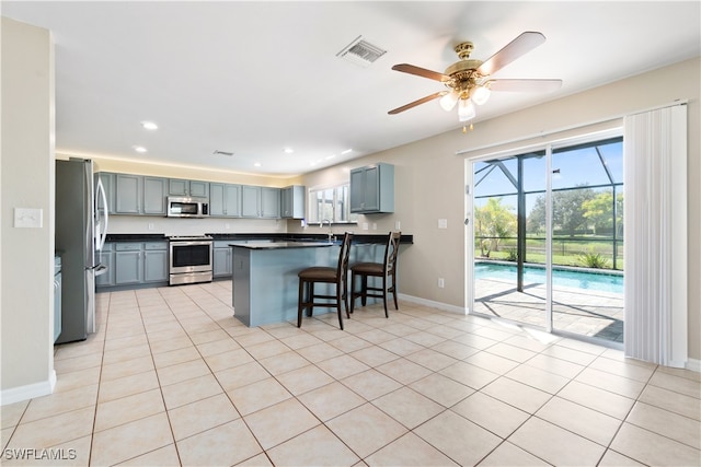 kitchen featuring appliances with stainless steel finishes, sink, kitchen peninsula, a breakfast bar, and light tile patterned flooring