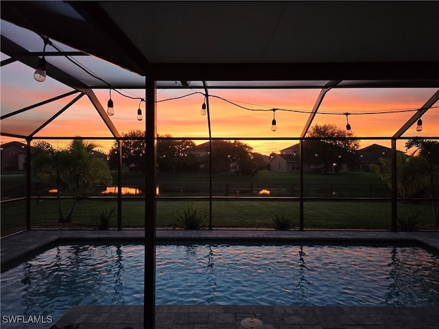 pool at dusk with glass enclosure and a lawn