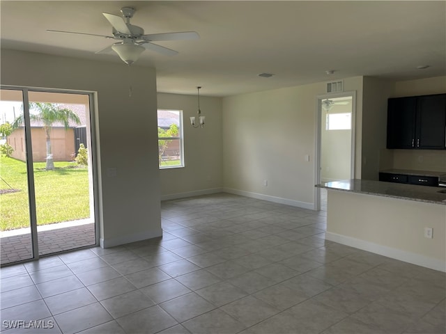 interior space featuring a healthy amount of sunlight, ceiling fan with notable chandelier, and light tile patterned floors