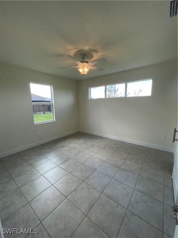 tiled spare room with a wealth of natural light and ceiling fan