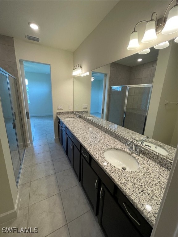 bathroom with a shower with door, vanity, and tile patterned floors