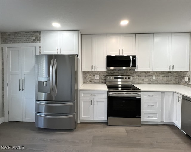 kitchen with appliances with stainless steel finishes, light wood-type flooring, and white cabinetry