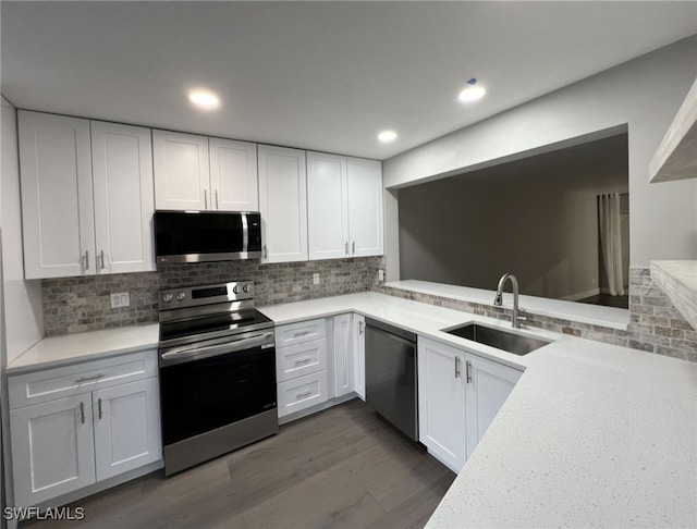 kitchen featuring decorative backsplash, dark wood-type flooring, stainless steel appliances, sink, and white cabinets